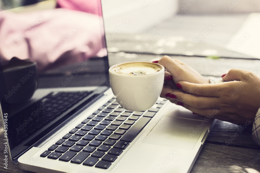 Womens hands with a cup of coffee and a laptop