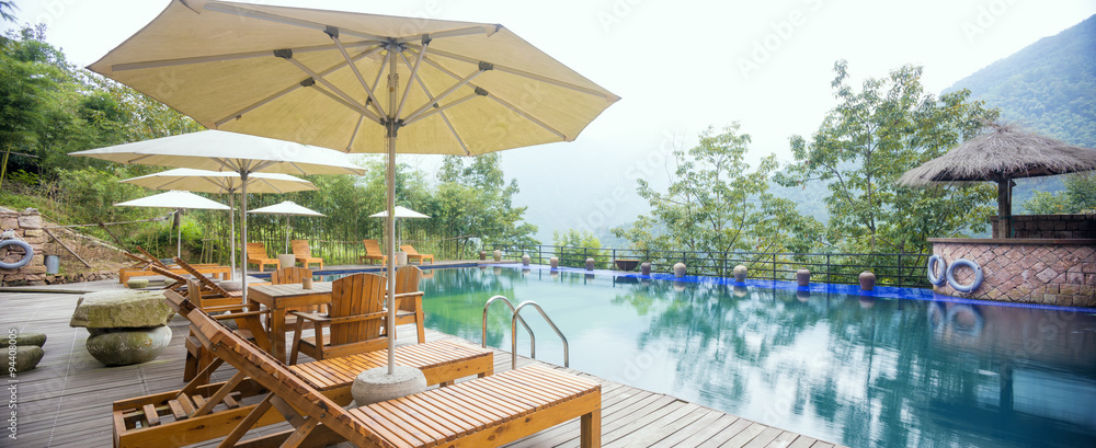 Umbrella chair in hotel pool resort with sunset