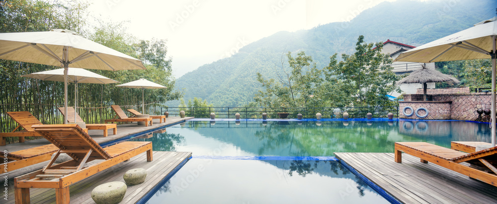 Umbrella chair in hotel pool resort with sunset