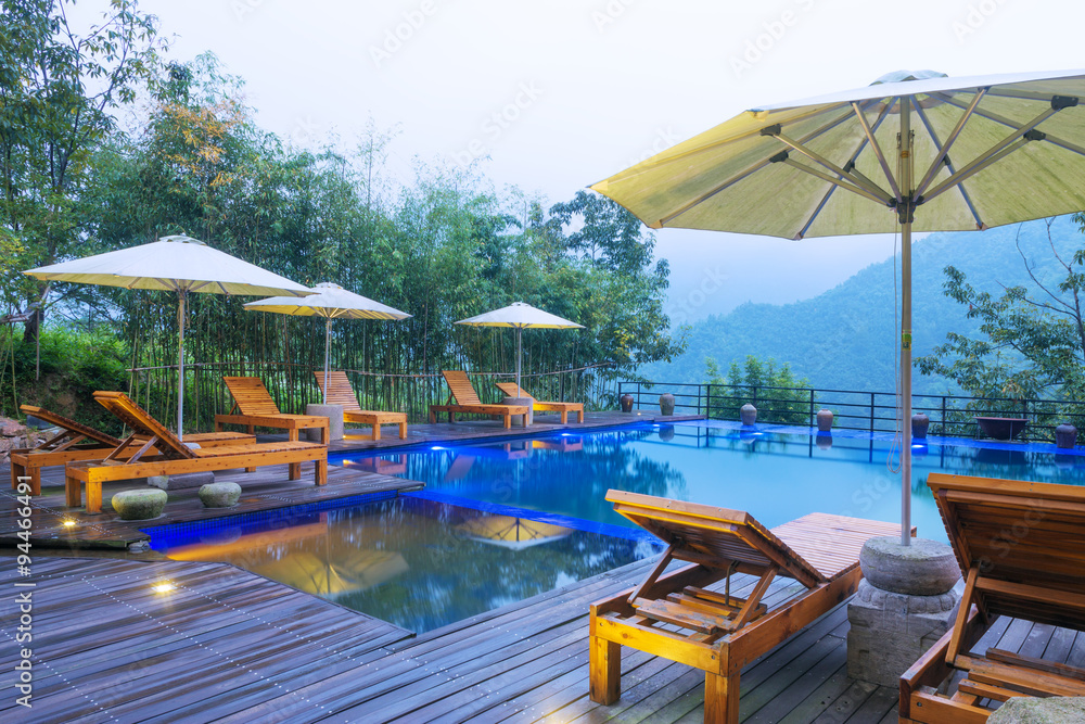 Umbrella chair in hotel pool resort with sunset