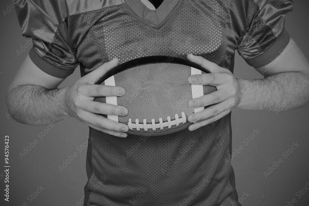 Composite image of american football player holding a ball