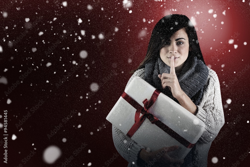 Composite image of brunette holding gift and keeping a secret