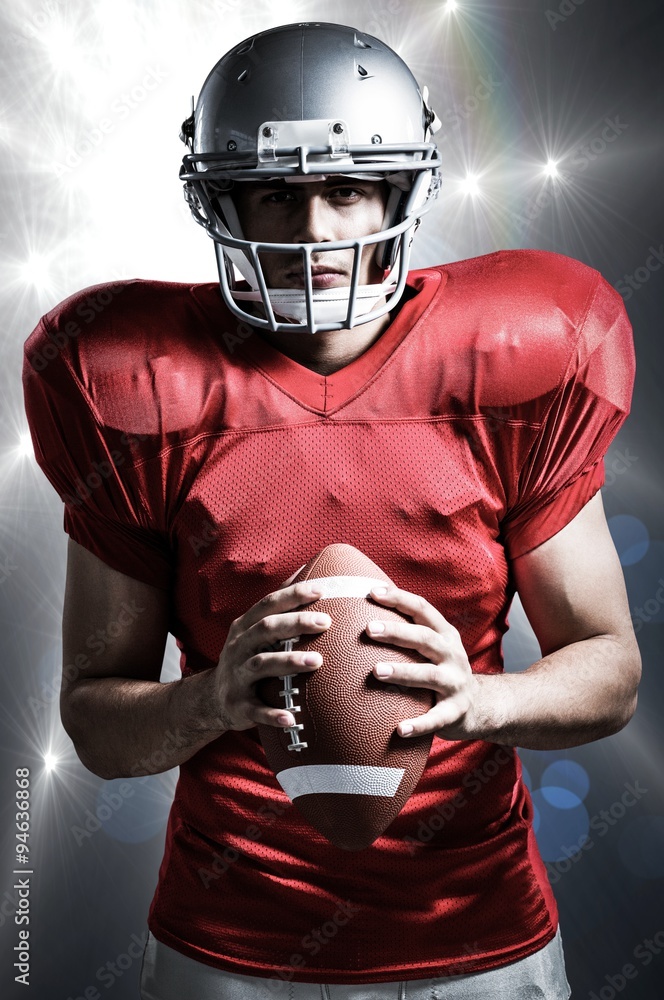 Composite image of american football player holding ball