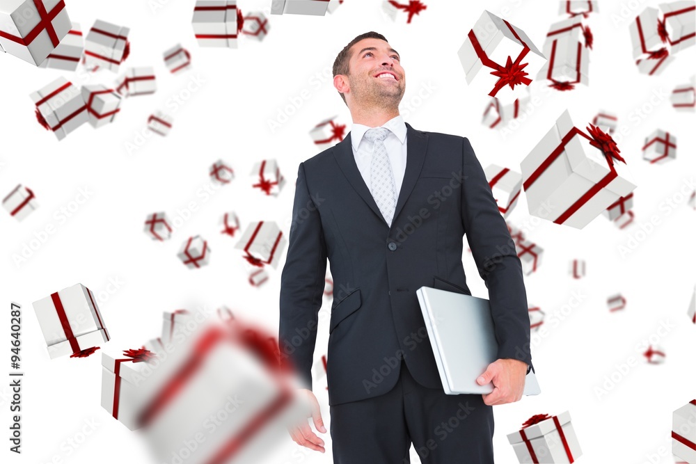 Composite image of businessman looking up holding laptop