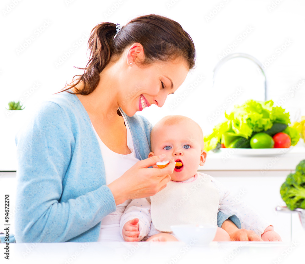 Mother feeding her baby girl with a spoon. Baby food