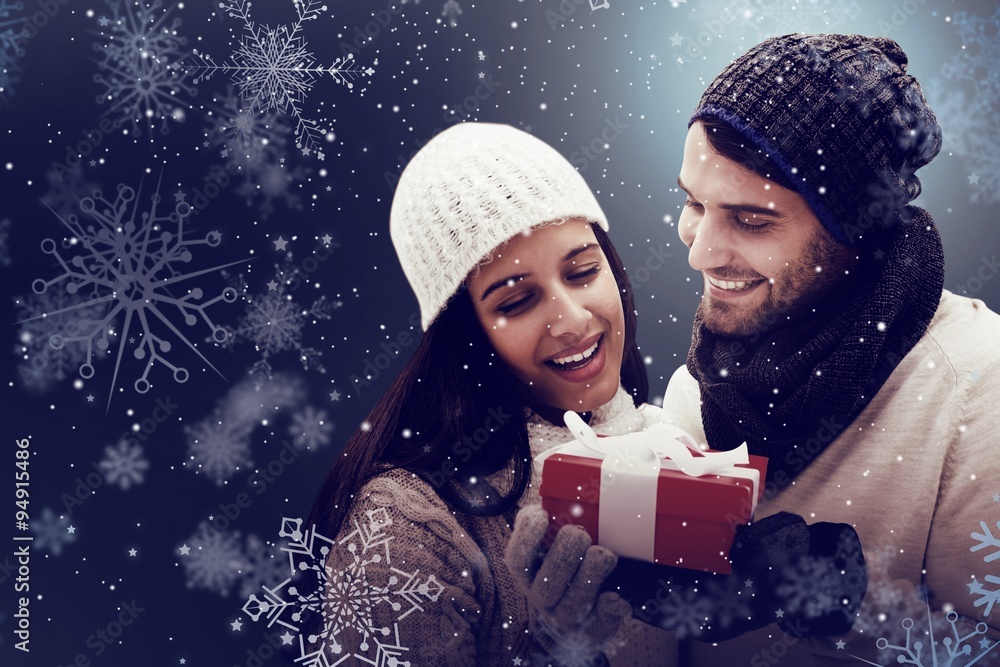 Composite image of winter couple holding gift