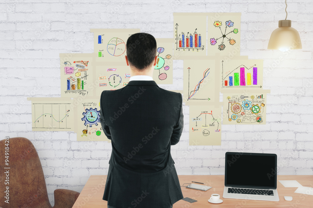 Businessman in front of brick wall with business scheme concept