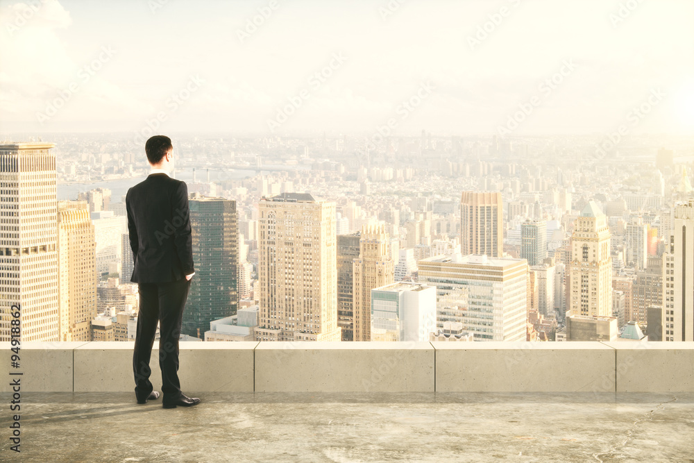 Businessman on the top of builng and looking at the city