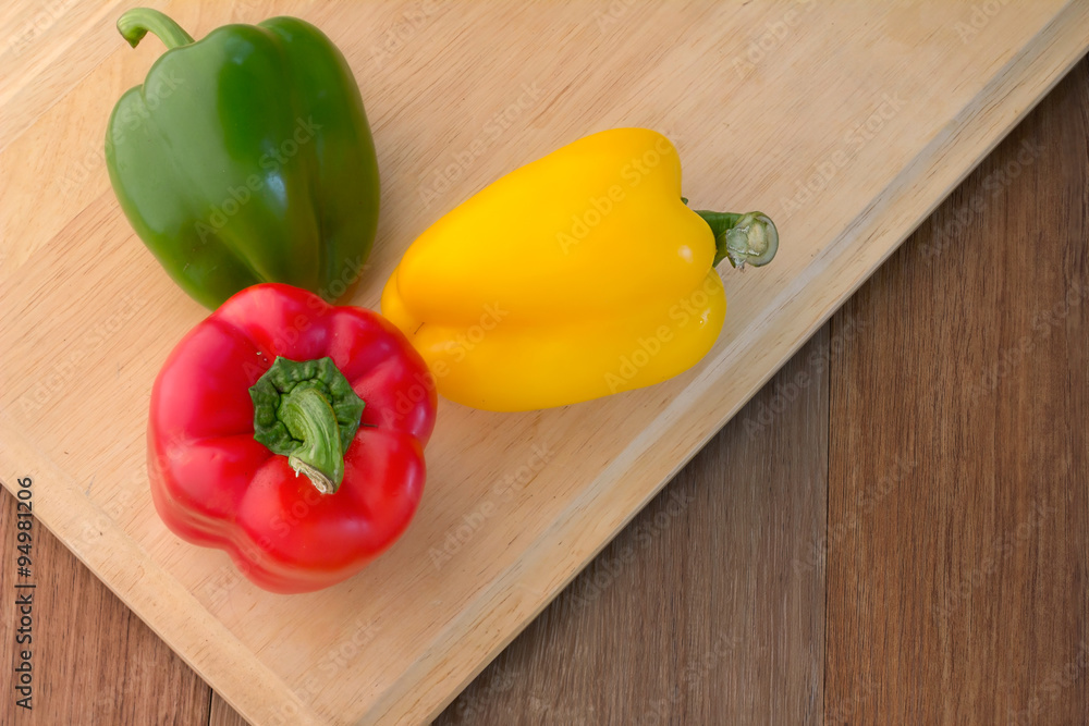 Three sweet peppers on a wooden background