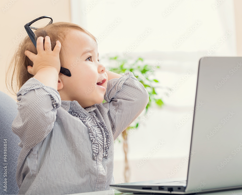 Toddler girl having a surprising moment while using her laptop