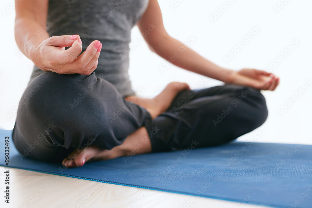 Woman in Lotus pose on exercise mat at gym