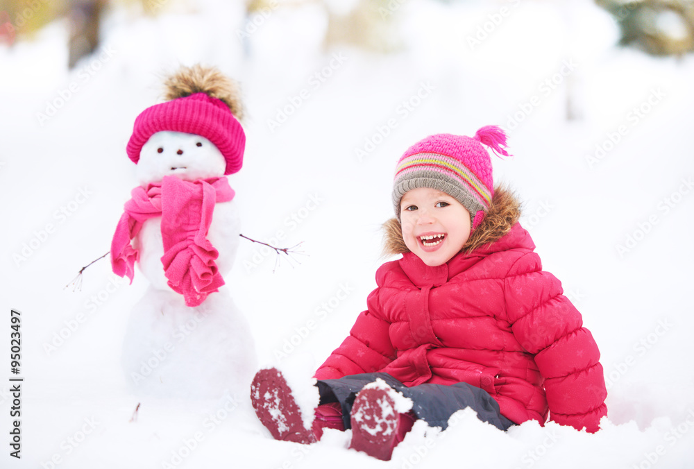 快乐的小女孩和雪人在冬天散步