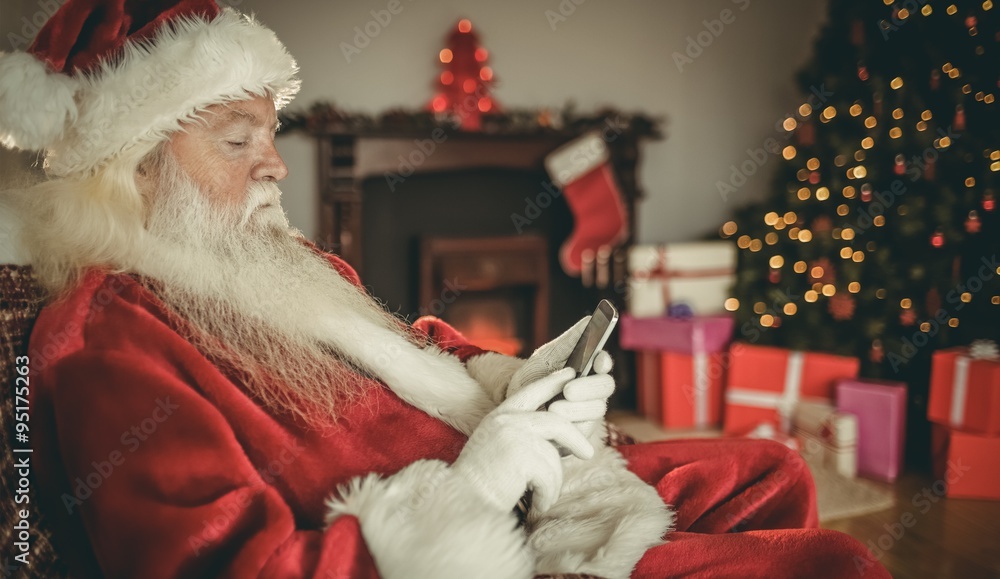 Concentrated santa using smartphone at christmas