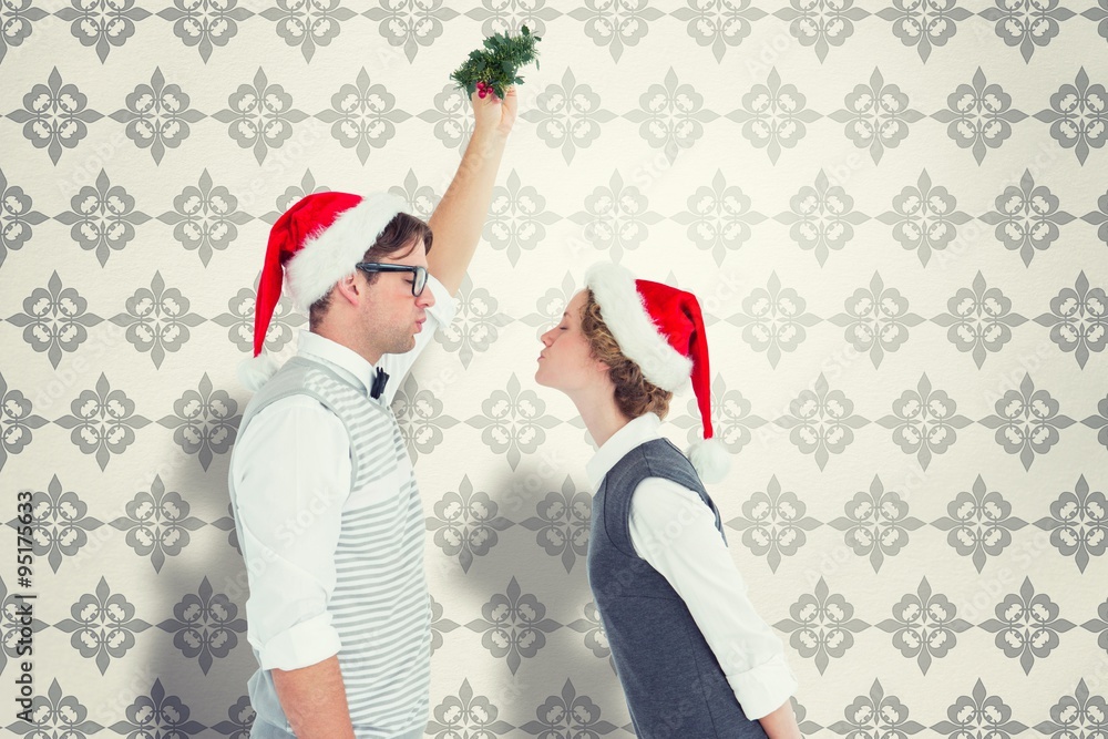 Composite image of geeky hipster kissing under mistletoe