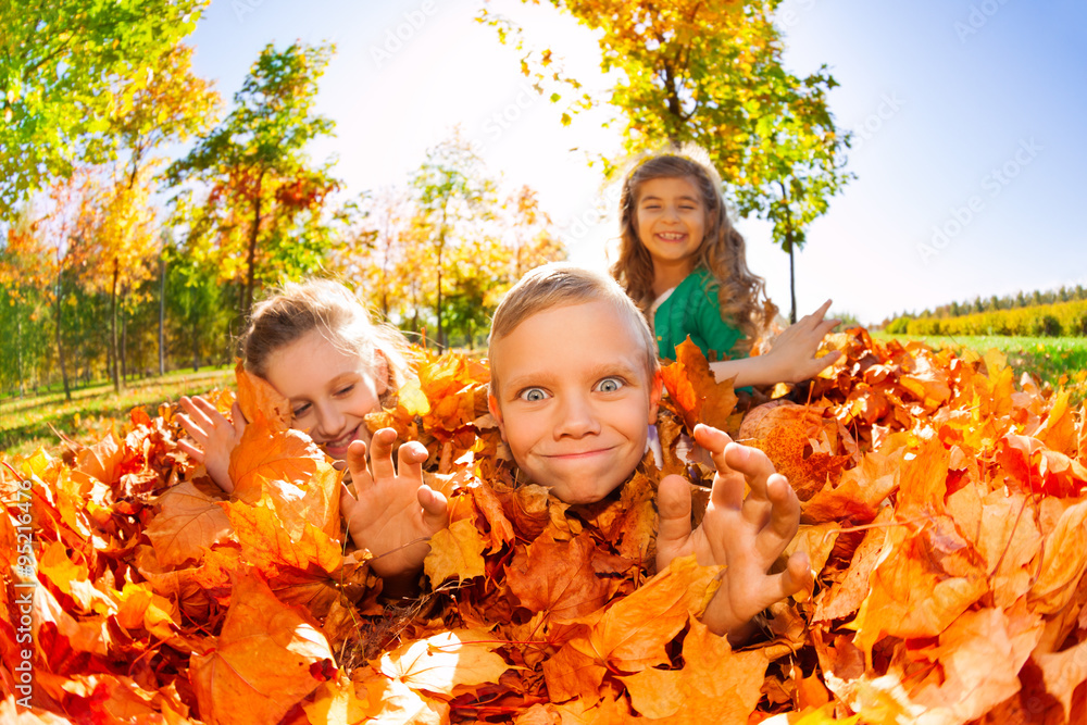 Children have fun laying on the ground with leaves