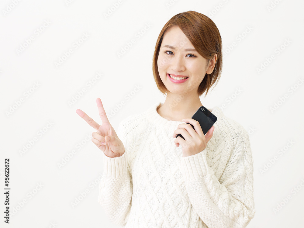 スマートフォンを持つ女性　ピースサイン