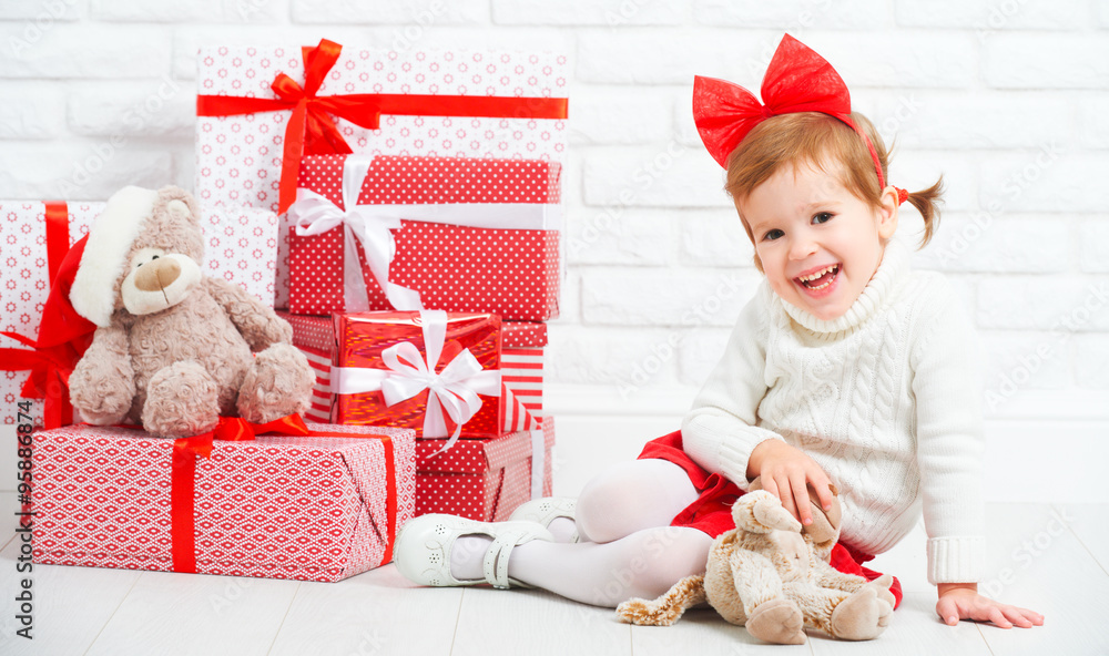 happy little girl child with Christmas gifts at wall