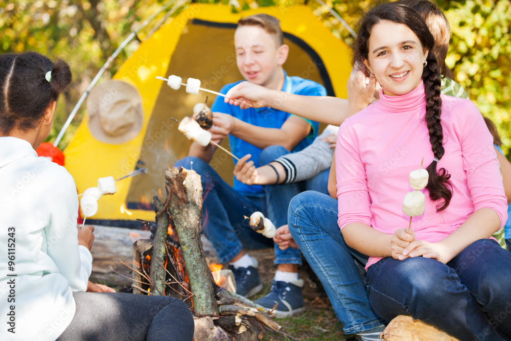 Friends with marshmallow on campsite near bonfire