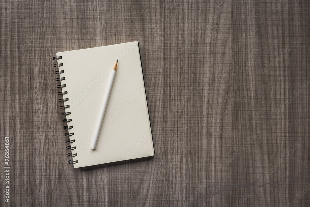 white pencil with blank notebook