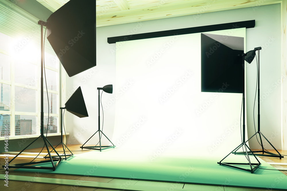 Empty photo studio with equipment and white background at sunset