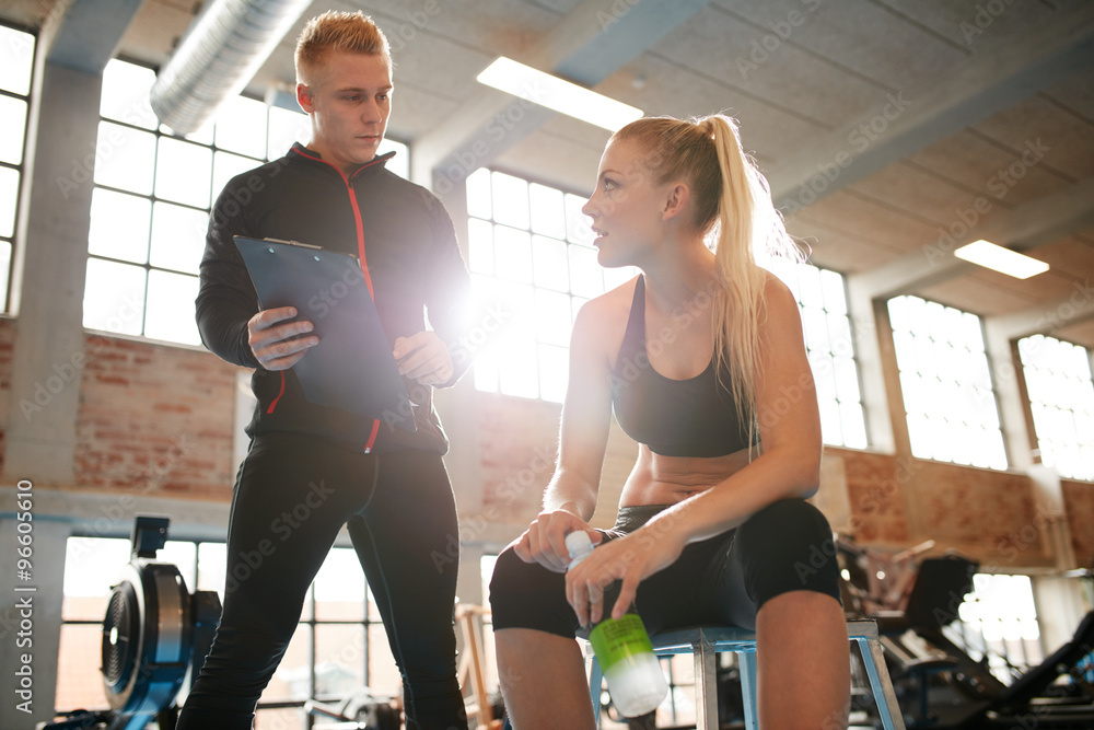 Young woman discussing exercise plan with her personal trainer