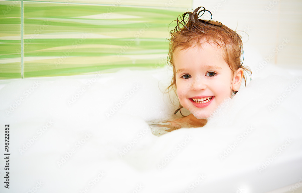 happy child girl bathes in  bath with foam and bubbles