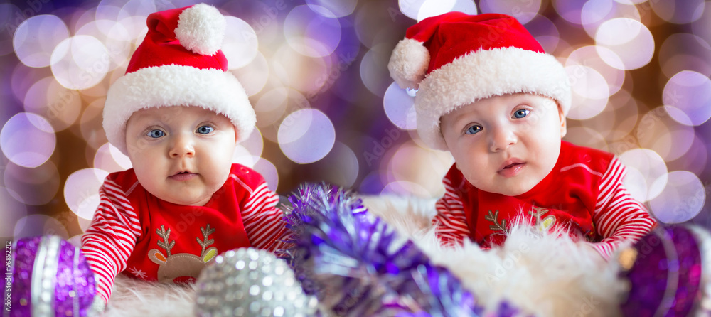 Baby twins - boy and girl in santa costumes for Christmas