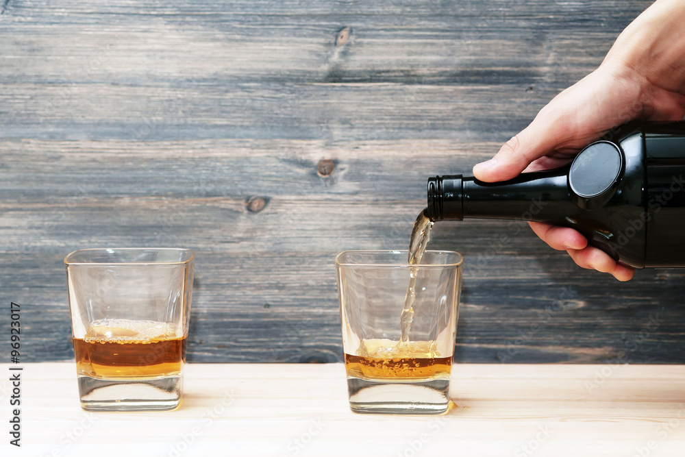 bartender pours two glasses of alcohol