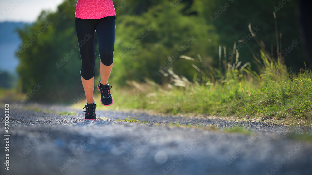 女运动员跑步者。鞋上特写。女性健身日落慢跑锻炼概念。