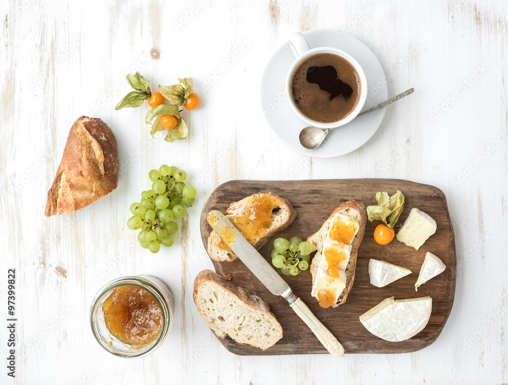 Breakfast set. Brie cheese and fig jam sandwiches with fresh grapes, ground cherries. Cup of coffee.