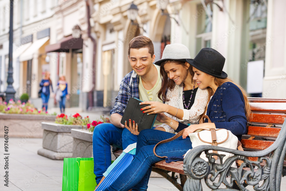 Friends sitting together with tablet on the bench