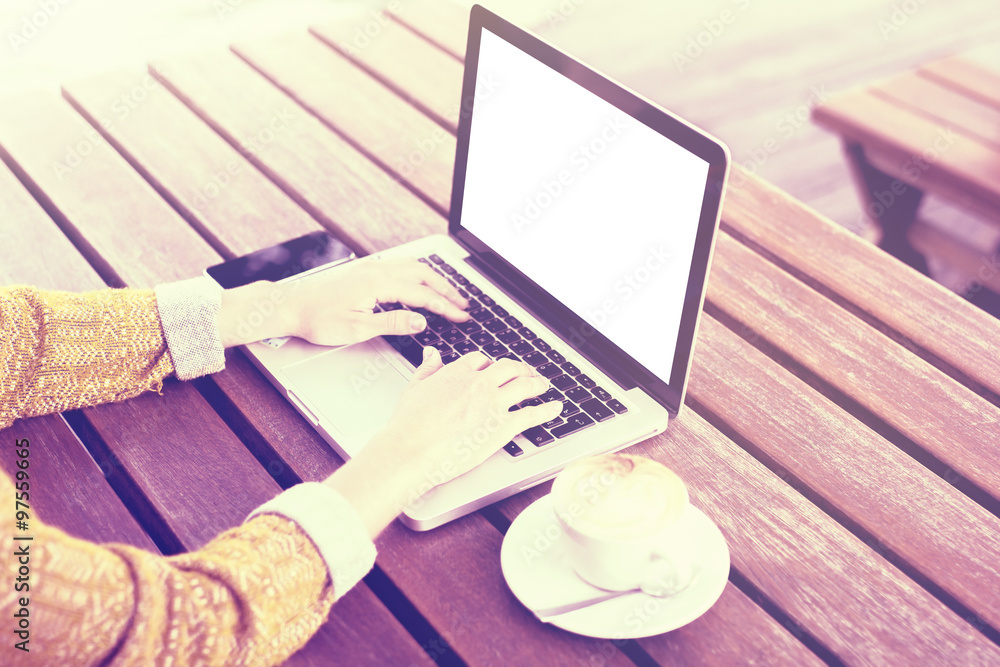 Girl with laptop, cell phone and cup of coffee on wooden table o