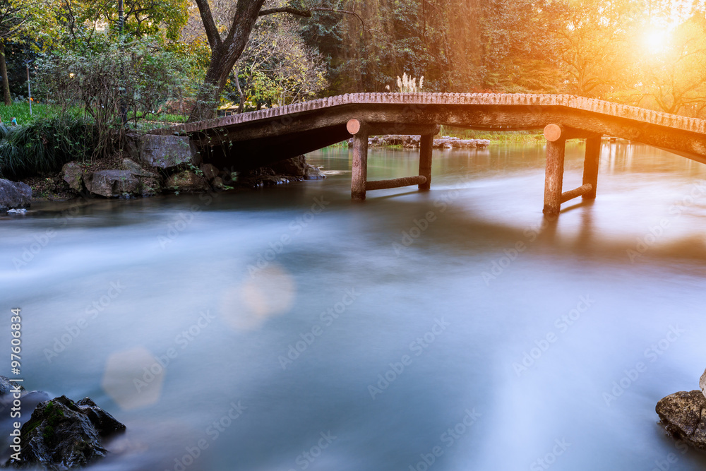 The stream and small Bridge in a Chinese garden in the sunset