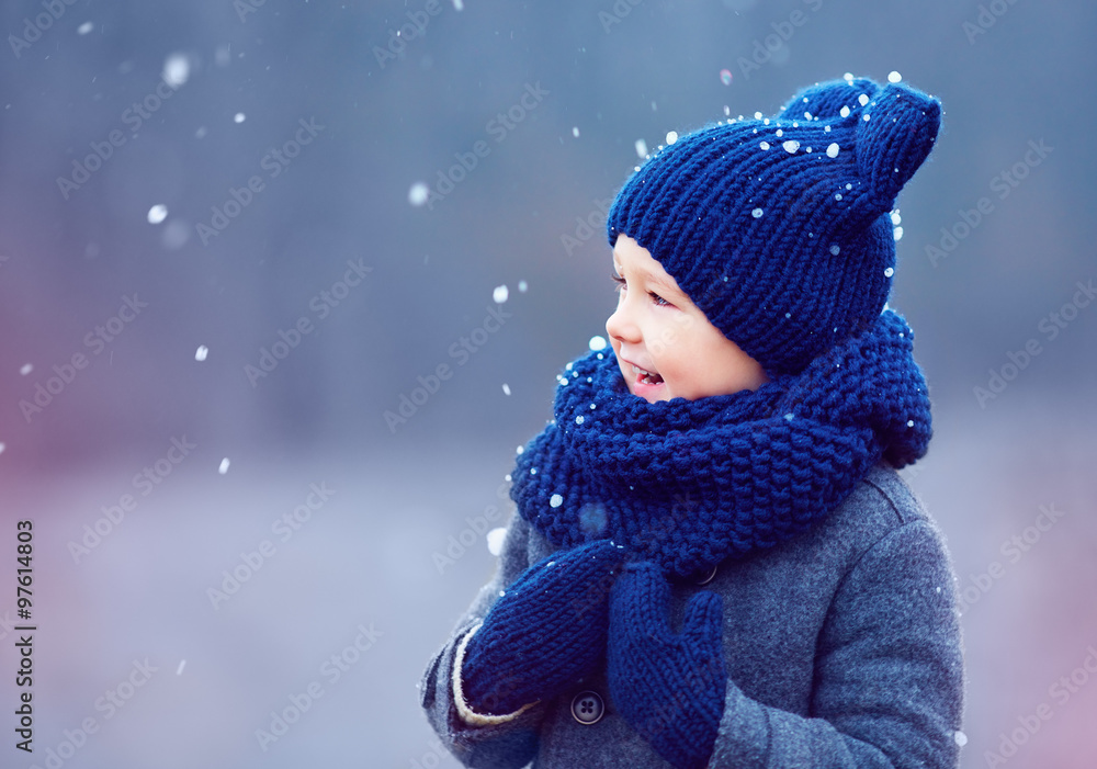 cute kid, boy in winter clothes playing under the snow