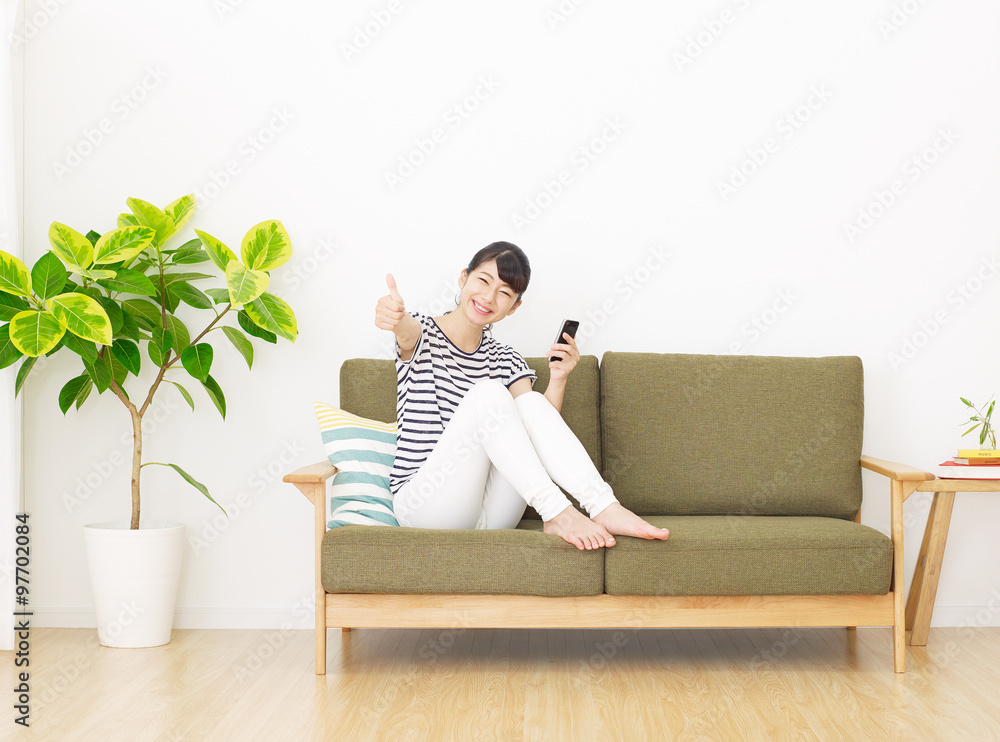 部屋でスマートフォンを使う女性　グッドサイン