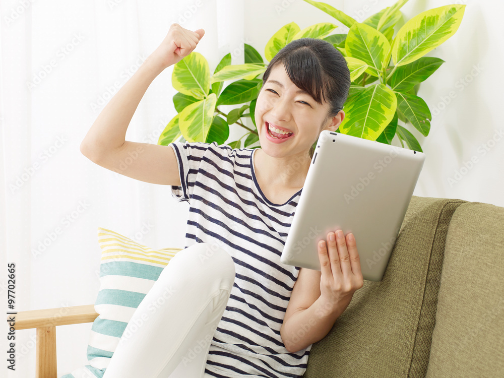 部屋でタブレットを使う女性　ガッツポーズ