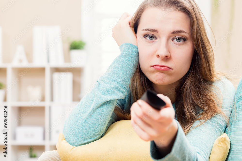 Bored young woman watching TV