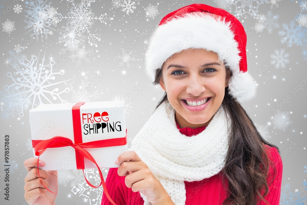 Composite image of festive brunette holding gift