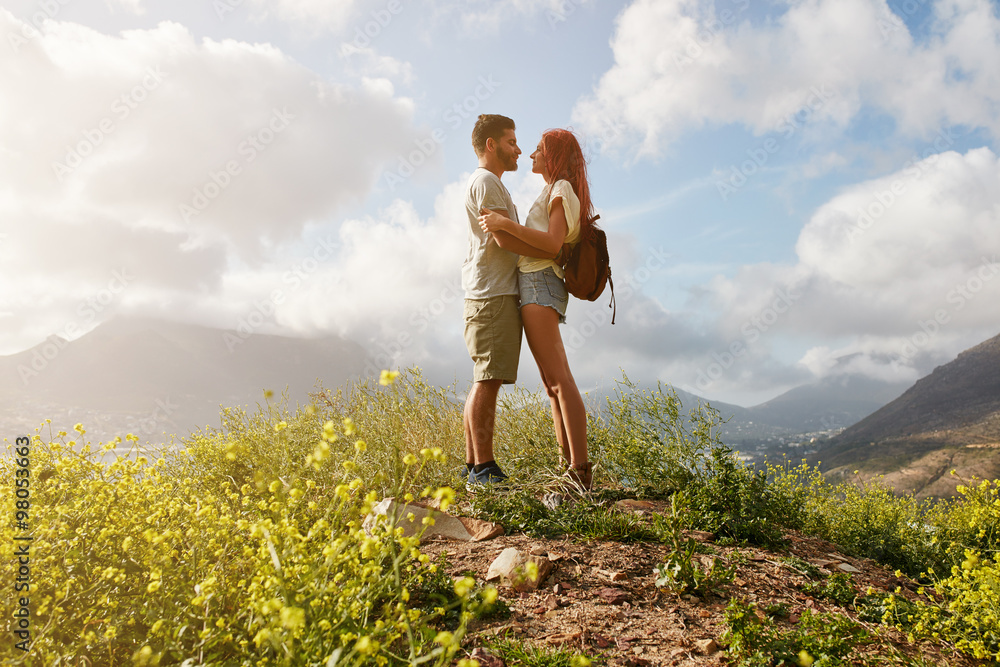 Amorous couple in embrace standing on a hill top