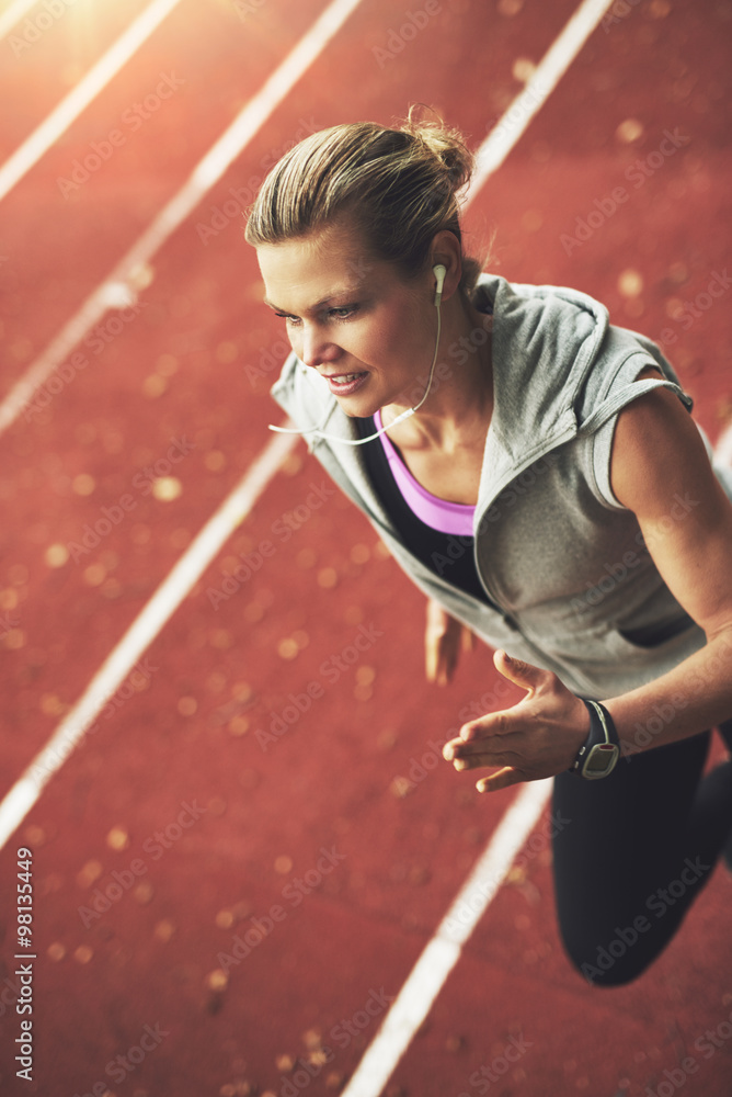 Close-up of athletic young woman running fast on stadium