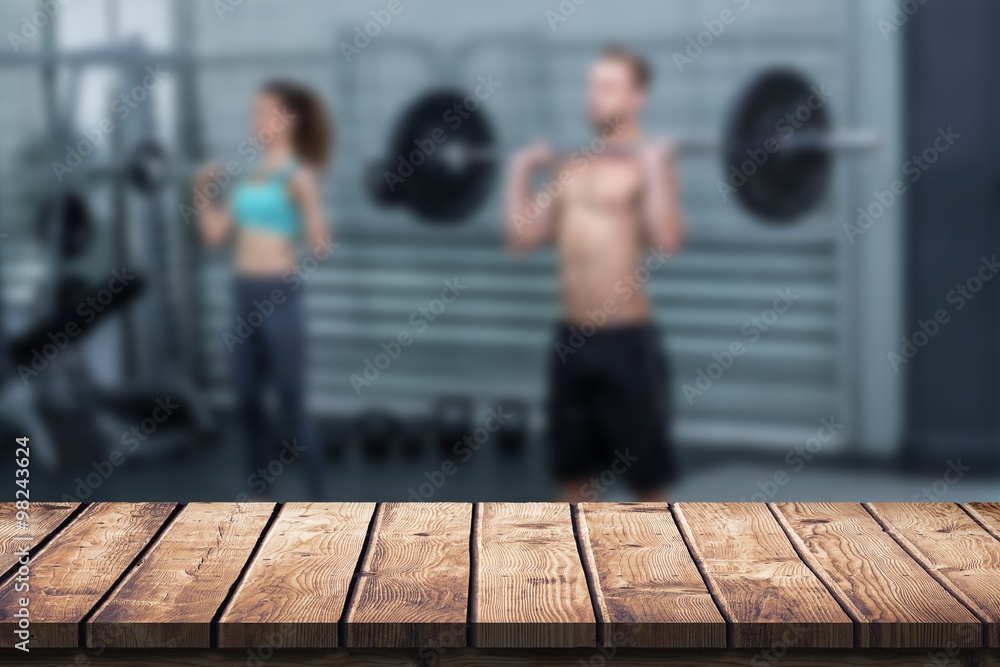 Composite image of muscular couple lifting weight together