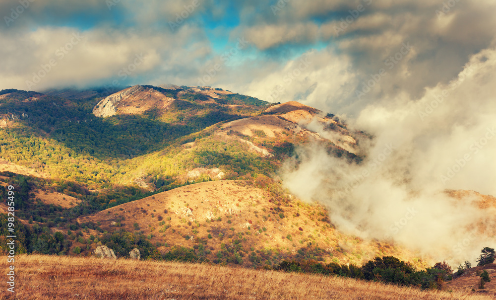 Dramatic mountain autumn landscape at sunset. Low clouds