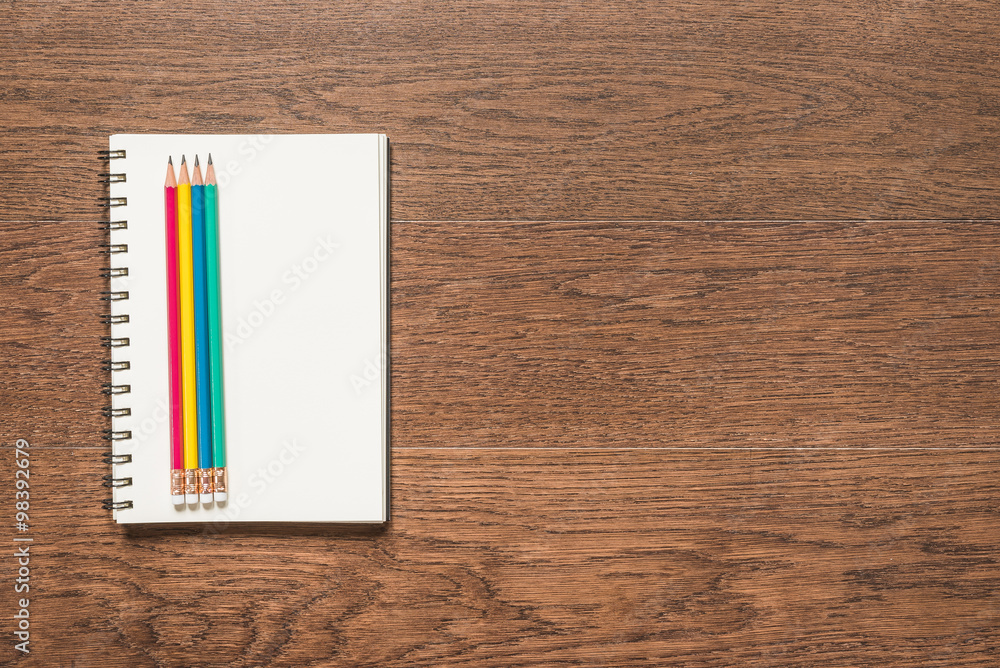 multicolor pencil with blank note book on wooden background