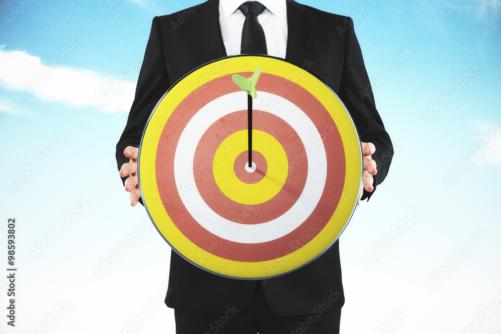 Businessman with bulls-eye and arrow at blue sky background