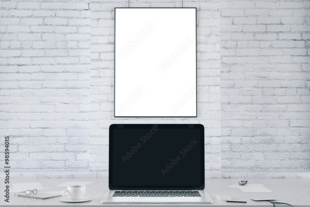 Blank picture frame on white brick wall and blank black laptop s