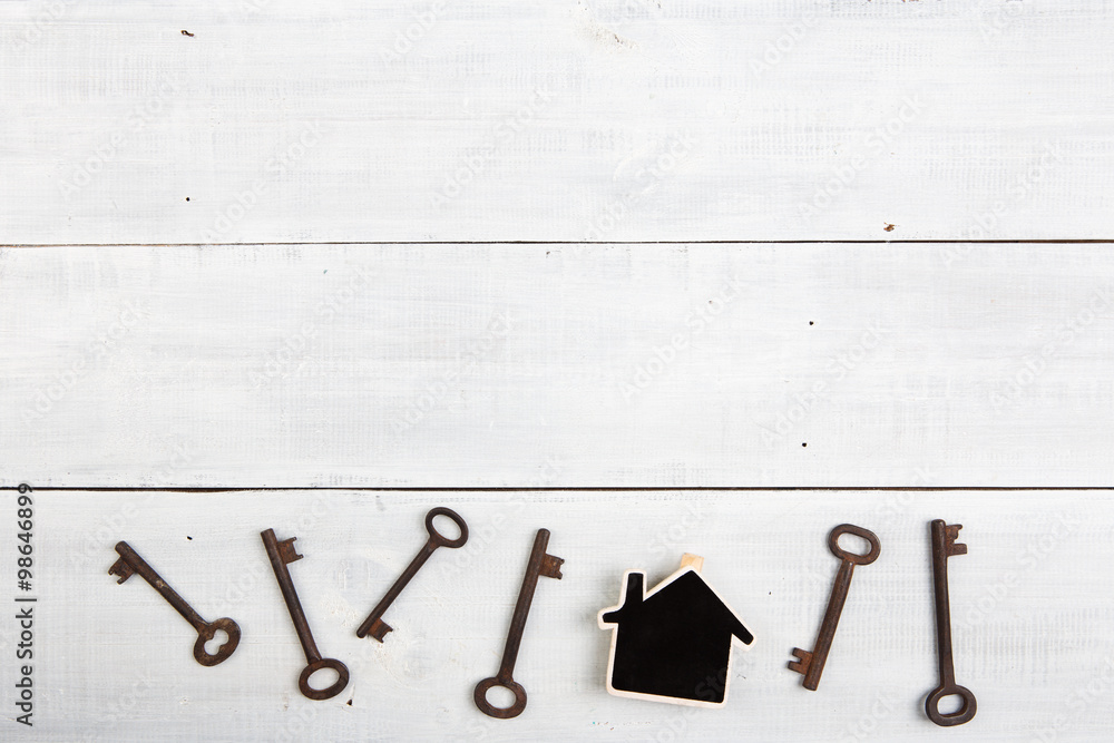 Real estate concept - little house and keys on white wooden desk