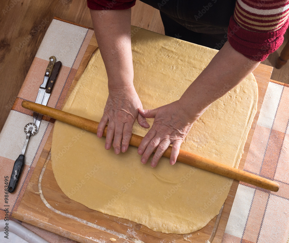 Woman rolling dough on a table in the kitchen