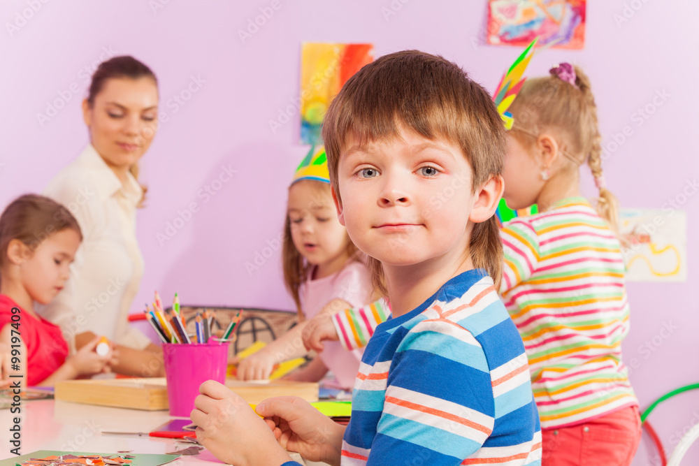 幼儿园班上和同伴一起坐在桌子旁的男孩