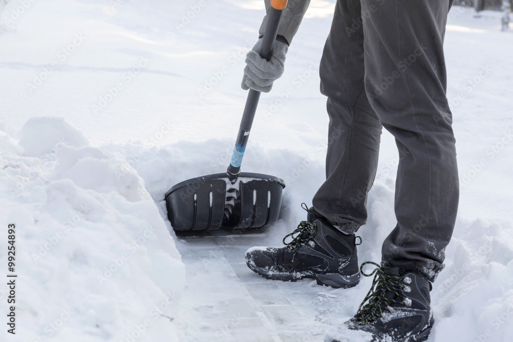 clearing snow with a shovel from sidewalk after blizzard