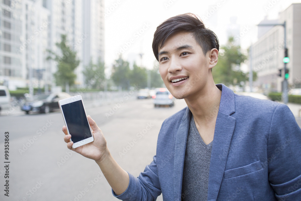 Young man waiting for taxi with smart phone